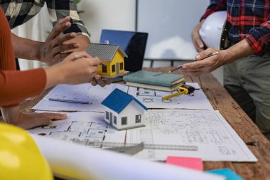 İnşaat mühendisleri, emlak sektöründeki evler veya ofis binaları için mühendislik araçları ve inşaat fikirleriyle büyük ticari binalar inşa etmek için planlar üzerinde çalışıyorlar. Yakın plan fotoğraf.