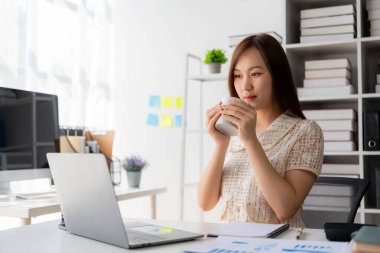 Vergi hesaplama tablosu raporları, şirket mali istatistikleri ve analitik araştırma fikirleri için hesap makinesi ve dizüstü bilgisayar kullanan Asyalı kadın çalışanlar