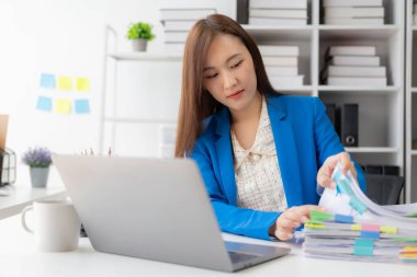 Vergi hesaplama tablosu raporları, şirket mali istatistikleri ve analitik araştırma fikirleri için hesap makinesi ve dizüstü bilgisayar kullanan Asyalı kadın çalışanlar