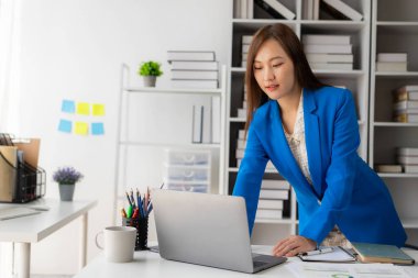 Vergi hesaplama tablosu raporları, şirket mali istatistikleri ve analitik araştırma fikirleri için hesap makinesi ve dizüstü bilgisayar kullanan Asyalı kadın çalışanlar