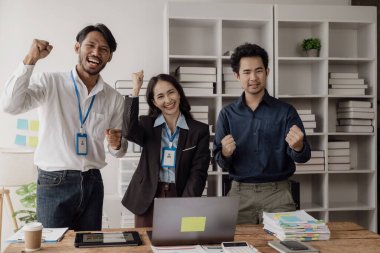 Asyalı İş Ekibi Meslektaşları, başarıyı kutlayan ve neşeli ve heyecanlı bir yaratıcılık içinde tasarım planlayan bir takım olarak çalışırlar ve başarılı bir girişim projesini alkışlamaktan mutluluk duyarlar..