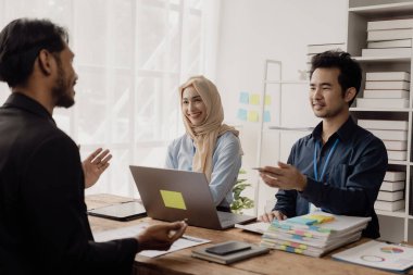 Zeki iş adamı ve İslami iş kadını masa stratejik planlamasında grup toplantılarında iş birliği yapıyor ve ofisteki meslektaşlarıyla beyin fırtınası yapıyor.