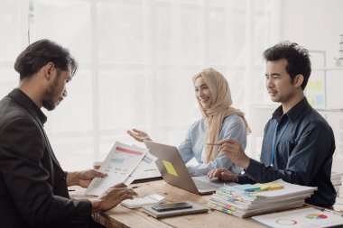 Zeki iş adamı ve İslami iş kadını masa stratejik planlamasında grup toplantılarında iş birliği yapıyor ve ofisteki meslektaşlarıyla beyin fırtınası yapıyor.