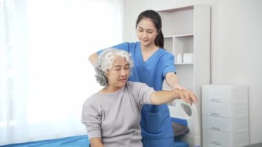 Yaşlı bir Asyalı kadına fizyoterapi uygulayan fizyoterapist, kadın bir doktorun sağlık hizmeti konseptiyle ağrılı kolu iyileştirmek için kadın hastanın yaralı kolunu muayene ediyor.