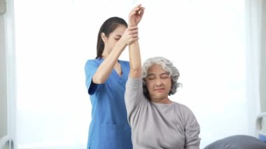 Yaşlı bir Asyalı kadına fizyoterapi uygulayan fizyoterapist, kadın bir doktorun sağlık hizmeti konseptiyle ağrılı kolu iyileştirmek için kadın hastanın yaralı kolunu muayene ediyor.