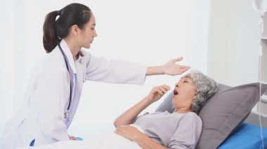 Asyalı hemşire hastane yatağında yaşlı Asyalı kadın hastayı kontrol ediyor. Çekici bakıcı, klinik 44k 60p 'de yaşlı büyükannesine danışmanlık ve danışmanlık yapar.