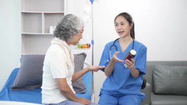 Asyalı hemşire hastane yatağında yaşlı Asyalı kadın hastayı kontrol ediyor. Çekici bakıcı, klinik 44k 60p 'de yaşlı büyükannesine danışmanlık ve danışmanlık yapar.