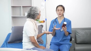 Asyalı hemşire hastane yatağında yaşlı Asyalı kadın hastayı kontrol ediyor. Çekici bakıcı, klinik 44k 60p 'de yaşlı büyükannesine danışmanlık ve danışmanlık yapar.