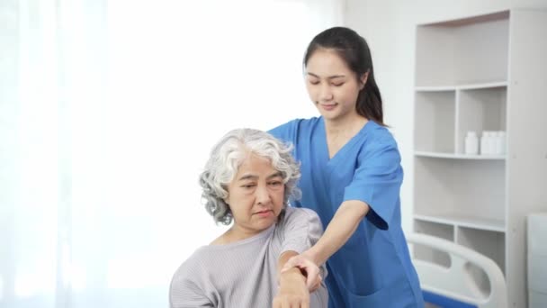 一名理疗师正在为一名年迈的亚洲妇女进行物理治疗 她正在检查女性病人受伤手臂的治疗情况 以便用女医生的概念来修复疼痛的手臂 — 图库视频影像