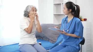 Asyalı hemşire hastane yatağında yaşlı Asyalı kadın hastayı kontrol ediyor. Çekici bakıcı, klinik 44k 60p 'de yaşlı büyükannesine danışmanlık ve danışmanlık yapar.
