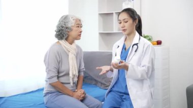 Asyalı hemşire hastane yatağında yaşlı Asyalı kadın hastayı kontrol ediyor. Çekici bakıcı, klinik 44k 60p 'de yaşlı büyükannesine danışmanlık ve danışmanlık yapar.
