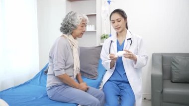 Asyalı hemşire hastane yatağında yaşlı Asyalı kadın hastayı kontrol ediyor. Çekici bakıcı, klinik 44k 60p 'de yaşlı büyükannesine danışmanlık ve danışmanlık yapar.