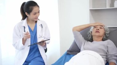 Asyalı hemşire hastane yatağında yaşlı Asyalı kadın hastayı kontrol ediyor. Çekici bakıcı, klinik 44k 60p 'de yaşlı büyükannesine danışmanlık ve danışmanlık yapar.