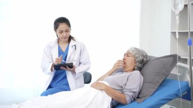 Asyalı hemşire hastane yatağında yaşlı Asyalı kadın hastayı kontrol ediyor. Çekici bakıcı, klinik 44k 60p 'de yaşlı büyükannesine danışmanlık ve danışmanlık yapar.