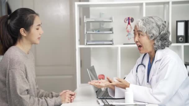 Starszy Azjatycki Lekarz Doradzający Młodej Azjatce Przy Stole Klinice Omawiający — Wideo stockowe
