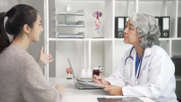 Старший Азіатський Лікар Консультує Молоду Азіатку Столом Клініці Обговорює Результати — стокове відео