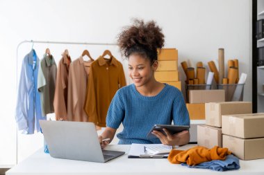 Siyahi kadın tasarımcı, bilgisayar işi, terzilik, moda, küçük işletme yaratıcılığı Afrikalı Amerikalı girişimci kız gülümseyip online siparişleri kontrol ediyor. Başarılı KOBİ iş fikri.