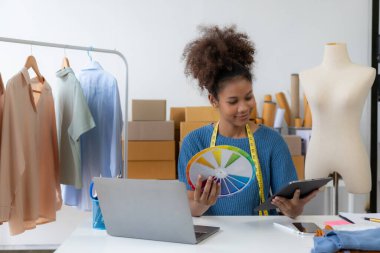Siyahi kadın tasarımcı, bilgisayar işi, terzilik, moda, küçük işletme yaratıcılığı Afrikalı Amerikalı girişimci kız gülümseyip online siparişleri kontrol ediyor. Başarılı KOBİ iş fikri.