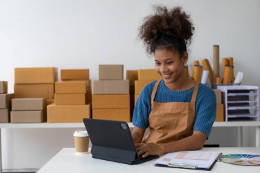 Siyahi kadın tasarımcı, bilgisayar işi, terzilik, moda, küçük işletme yaratıcılığı Afrikalı Amerikalı girişimci kız gülümseyip online siparişleri kontrol ediyor. Başarılı KOBİ iş fikri.