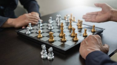 Satranç oyununu, yeni strateji planı, takım çalışması konsepti ve başarılı bir yarışmada satranç taşlarını hareket ettiren işadamlarının elleriyle kapatıyoruz. Yönetim stratejisi veya liderlik kavramı