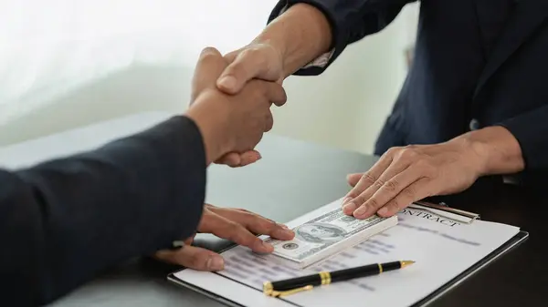 Government officials receive bribes from businessmen who have ideas about corruption and anti-bribery. Businessman\'s hand holding bribe to official signing contract for business project