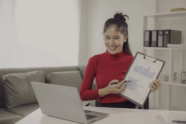 Asian woman using calculator and laptop to do finance, accounting, statistics and analytical research concept to calculate business principles, accounting statistics at office