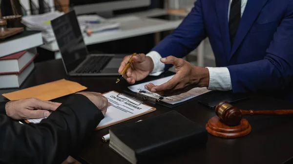 Attorneys work with clients in the office and speak with clients to discuss legal details. Close-up of a judge with a gavel and a professional lawyer discussing a legal case.