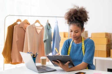 Başlangıç, küçük işletmeler, akıllı telefon ya da dizüstü bilgisayar kullanan Afrikalı kadın işletme sahibi paketlenmiş ürünleri hazırlamak için online siparişler alıyor ve onaylıyor. KOBİ iş kavramı