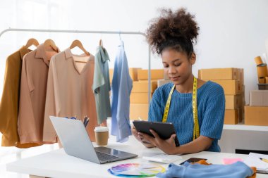 Başlangıç, küçük işletmeler, akıllı telefon ya da dizüstü bilgisayar kullanan Afrikalı kadın işletme sahibi paketlenmiş ürünleri hazırlamak için online siparişler alıyor ve onaylıyor. KOBİ iş kavramı