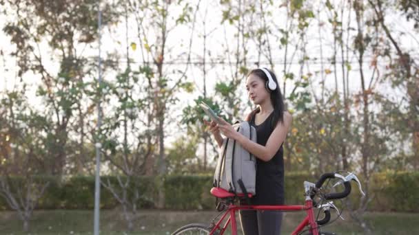 Asyalı Kadın Sırtında Sırt Çantasıyla Parkta Egzersiz Yapmak Için Bisiklete — Stok video