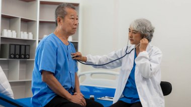 Kıdemli bayan doktor kalp atışlarını kontrol etmek için steteskop kullanıyor. Kıdemli doktor hastanede kalp atışlarını steteskop kullanarak kontrol ediyor. Yaşlı sağlık hizmetleri kavramı.