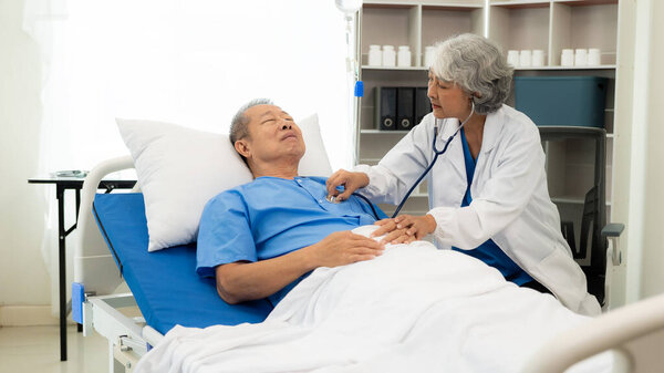 Старшая женщина-врач использует стетоскоп, чтобы проверить сердцебиение. Старший слушает сердцебиение при помощи стетоскопа в больнице для обследования. Концепция здравоохранения для пожилых людей.