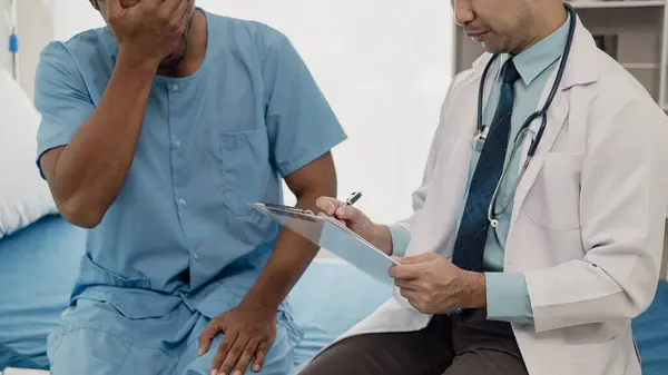 Doctor talking with patient in hospital, male patient lying in bed and doctor providing care, giving advice and encouragement, medical health concept