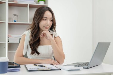 Dizüstü bilgisayar üzerinde çalışan ve evrak işleri yapan Asyalı kadın muhasebeci, vergi, ticaret ve mali danışmanlık ve muhasebe analizi yatırım bilgileri finans kavramları ve vergi sistemi