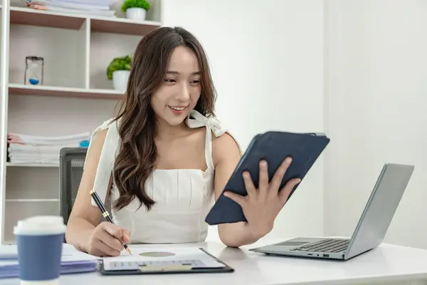 Asian female accountant working on laptop and doing paperwork, tax, trading, and financial consulting and accounting analysis investment information report Financial concepts and tax system