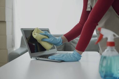 Asyalı kadın ev işi yapıyor önlük takıyor oturma odasının ahşap zeminini temizliyor Mutlu ev kadını evde ev işi yapıyor çekici bir gülümsemeyle, ev temizliği konseptiyle