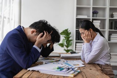 Çok yorgun, stresli ve meşgul iş adamları ofis masasında oturuyorlar, başlarını tutuyorlar ve masadaki bir sürü iş belgelerini görmezden geliyorlar, başarısız iş konsepti..