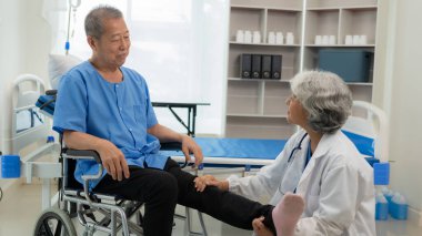 Yaşlı bir Asyalı adam oturma odasında yaşlı bir kadın hemşirenin desteğiyle fizik tedavi uyguluyor..