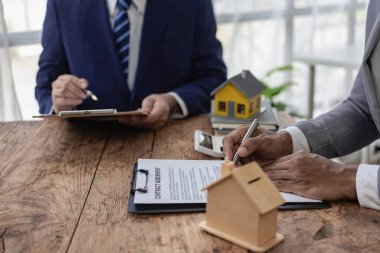 Satılık konut projesi ve konut projelerindeki satış elemanlarıyla detayları ve tavsiyeleri tartışıyorlar. Gayrimenkul ticareti konsepti. Yakın plan resimler.