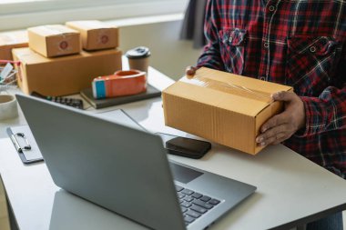 Küçük işletme girişimcisi, KOBİ, bağımsız erkek, evden çalışıyor. Ticari denetimler için akıllı telefonlar ve dizüstü bilgisayarlar kullanın çevrimiçi pazarlama KOBİ paketleme kutusu konsepti e-ticaret ekibi yakın çekim fotoğraf
