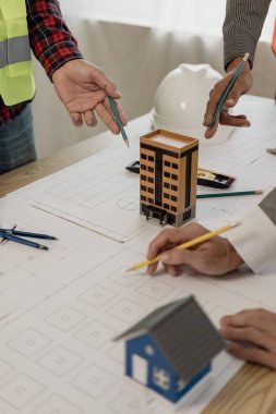 Mimari proje mühendisinin resimleri ortaklarla ve mühendislik araçlarıyla bir araya gelir ve tartışılacak çizimlere işaret eder. Mühendislik araçları ve inşaat kavramları dikey resim
