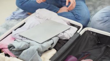 Asyalı bir çift, yurtdışı seyahati için kıyafetlerini oturma odasının zemininde bavullara doldurup tatil için hazırlanıyorlar..