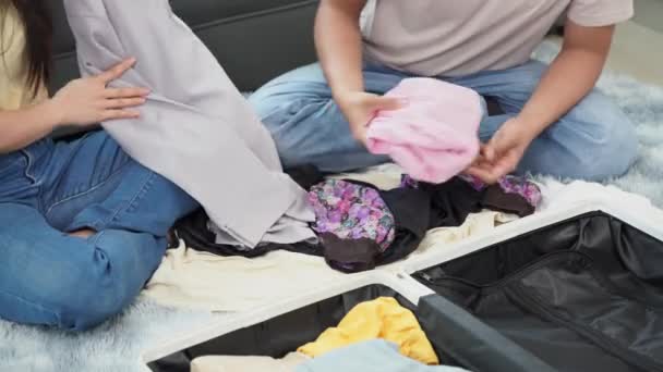 아시아 커플은 휴가를 준비하면서 바닥에 가방에 여행을 포장합니다 — 비디오