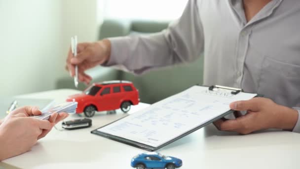 営業担当者 自動車保険またはレンタルドキュメントにサインする人 契約書または契約書にサインを書いて テーブルの上に新しい車のキーを購入または販売します 保証について — ストック動画