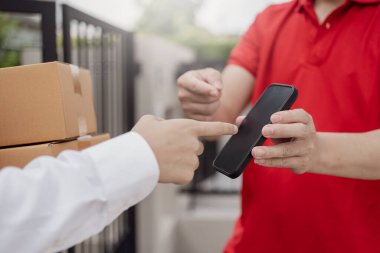 Lojistik konsepti A paketi ya da teslimat servisi çevrimiçi alışveriş, nakliye ya da e-ticaret için bir hizmet sağlayıcısının ya da ürünün kapısında duruyor. - Cep telefonuyla ödeme yaparken yakın plan görüntüsü