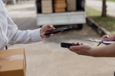 Lojistik konsepti A paketi ya da teslimat servisi çevrimiçi alışveriş, nakliye ya da e-ticaret için bir hizmet sağlayıcısının ya da ürünün kapısında duruyor. - Cep telefonuyla ödeme yaparken yakın plan görüntüsü