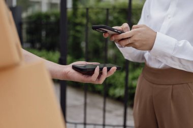 Lojistik konsepti A paketi ya da teslimat servisi çevrimiçi alışveriş, nakliye ya da e-ticaret için bir hizmet sağlayıcısının ya da ürünün kapısında duruyor. - Cep telefonuyla ödeme yaparken yakın plan görüntüsü