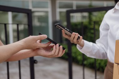 Lojistik konsepti A paketi ya da teslimat servisi çevrimiçi alışveriş, nakliye ya da e-ticaret için bir hizmet sağlayıcısının ya da ürünün kapısında duruyor. - Cep telefonuyla ödeme yaparken yakın plan görüntüsü