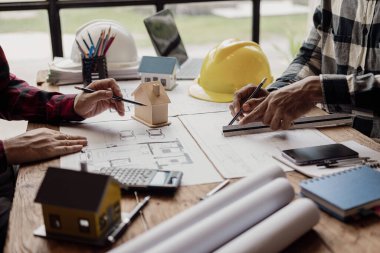 Uzmanlardan oluşan çeşitli bir ekip, inşaat mühendisleri, mimarlar, iş yatırımcıları ve genel işçilerle birlikte ayrıntılı planları tartışan bir emlak inşaat projesi üzerinde çalışıyor.