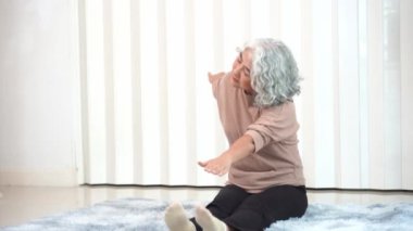 Spor elbiseli, yoga ve spor egzersizi yapan emekli Asyalı son sınıf öğrencisi bir kadın. Dairedeki oturma odasında dinlenmek için. Yaşlı kadın her gün egzersiz yaparak sağlığını koruyor.